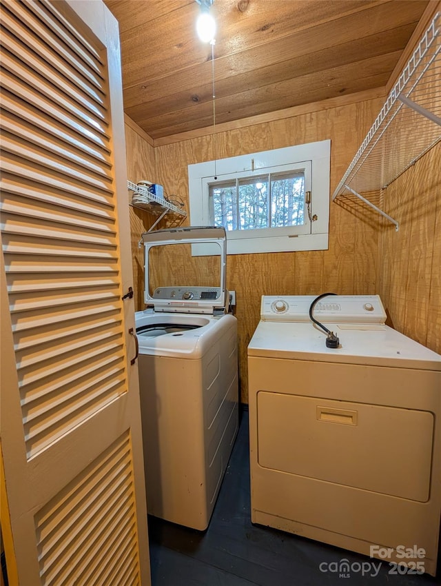 laundry area with wooden walls, washing machine and dryer, and laundry area