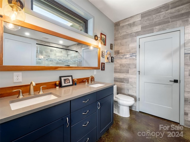 bathroom with vanity, toilet, concrete flooring, and tile walls