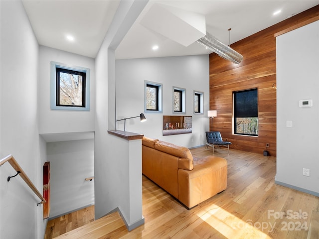 living room with wood walls, high vaulted ceiling, and light wood-type flooring