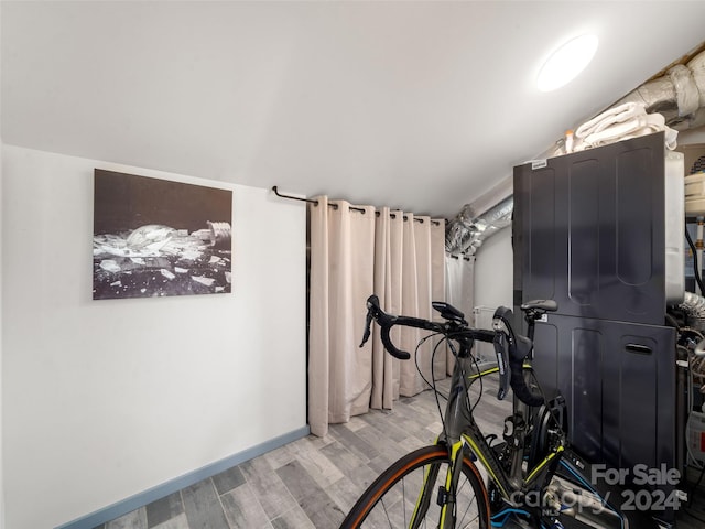 exercise room with wood-type flooring and vaulted ceiling