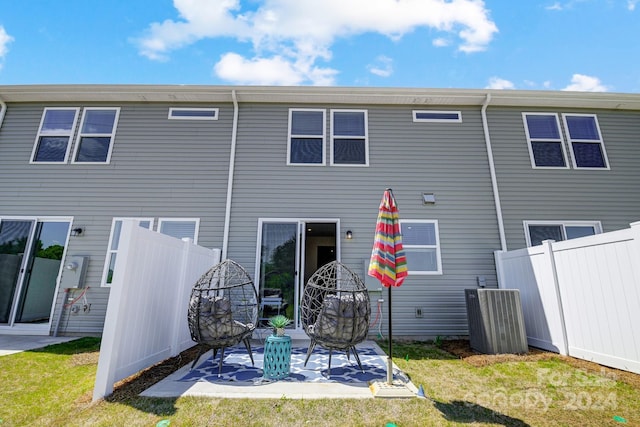 rear view of house featuring a lawn, central AC unit, and a patio