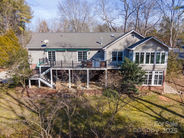 rear view of property with a yard, a deck, and a sunroom