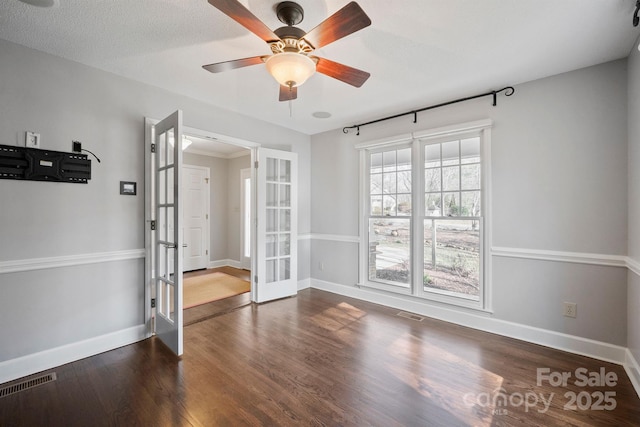 unfurnished room with a textured ceiling, dark wood-type flooring, french doors, and ceiling fan