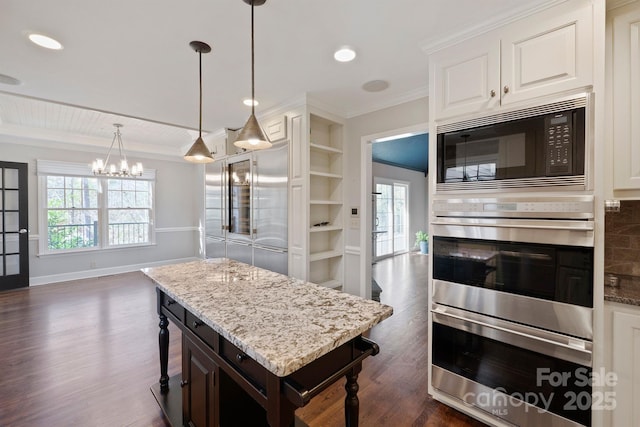 kitchen with white cabinetry, dark hardwood / wood-style floors, built in appliances, ornamental molding, and a kitchen bar