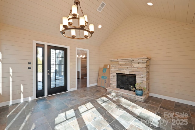 unfurnished living room featuring an inviting chandelier, wood ceiling, wooden walls, and an outdoor stone fireplace