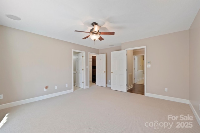 unfurnished bedroom featuring ceiling fan, light carpet, and ensuite bath