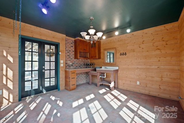 unfurnished office featuring french doors, a chandelier, and wood walls