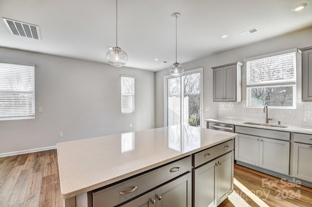 kitchen featuring light stone countertops, a center island, light hardwood / wood-style floors, and sink