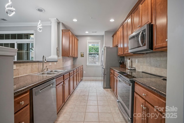 kitchen with decorative light fixtures, stainless steel appliances, dark stone countertops, and sink