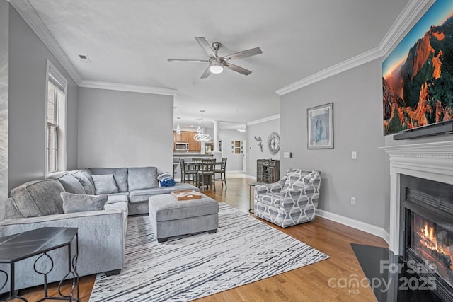 living room featuring hardwood / wood-style floors, ceiling fan, and ornamental molding