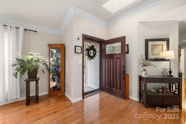 entryway with a skylight, light hardwood / wood-style flooring, and ornamental molding