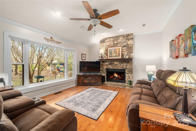 living room with hardwood / wood-style floors, a stone fireplace, ceiling fan, and lofted ceiling