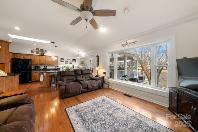 living room with ceiling fan, lofted ceiling, crown molding, and light hardwood / wood-style flooring