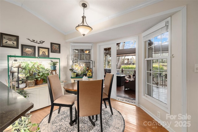 dining space featuring a textured ceiling, lofted ceiling, ornamental molding, and light hardwood / wood-style flooring