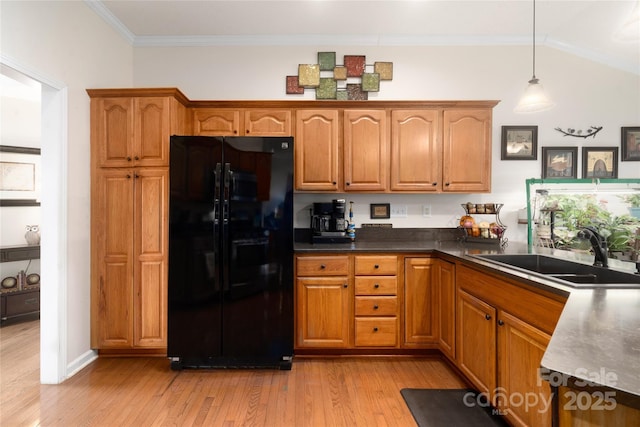 kitchen featuring black refrigerator, sink, light hardwood / wood-style flooring, ornamental molding, and decorative light fixtures