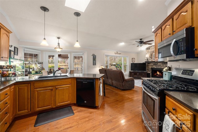 kitchen featuring lofted ceiling with skylight, sink, light hardwood / wood-style flooring, appliances with stainless steel finishes, and decorative light fixtures