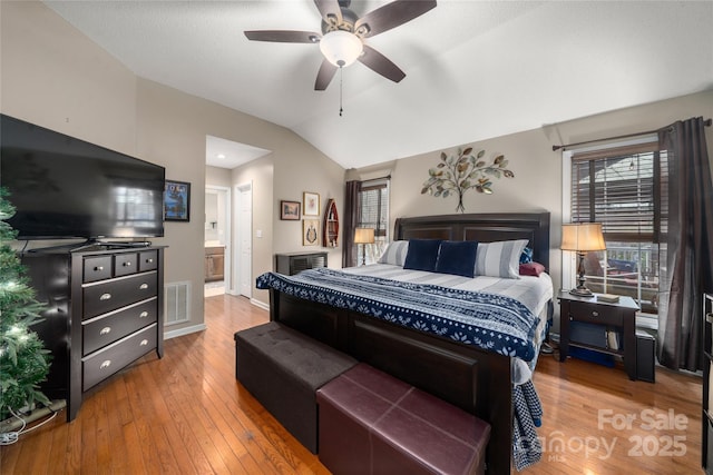 bedroom with ceiling fan, ensuite bathroom, vaulted ceiling, and hardwood / wood-style flooring