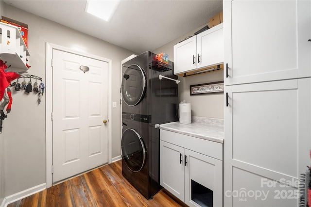 washroom with cabinets, dark hardwood / wood-style flooring, and stacked washing maching and dryer