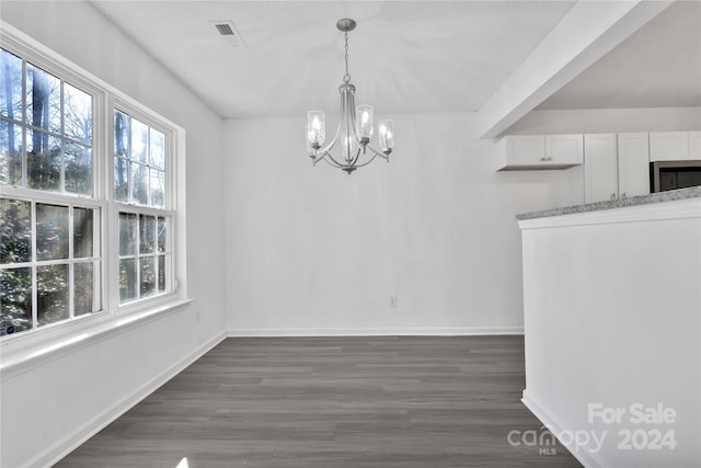 unfurnished dining area featuring dark hardwood / wood-style floors and an inviting chandelier