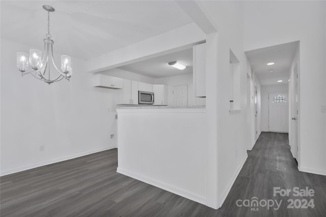 kitchen featuring white cabinetry, dark wood-type flooring, a notable chandelier, kitchen peninsula, and decorative light fixtures