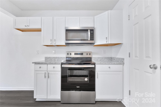 kitchen with dark hardwood / wood-style flooring, stainless steel appliances, white cabinetry, and light stone counters