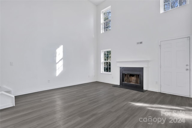 unfurnished living room featuring a high ceiling and dark wood-type flooring