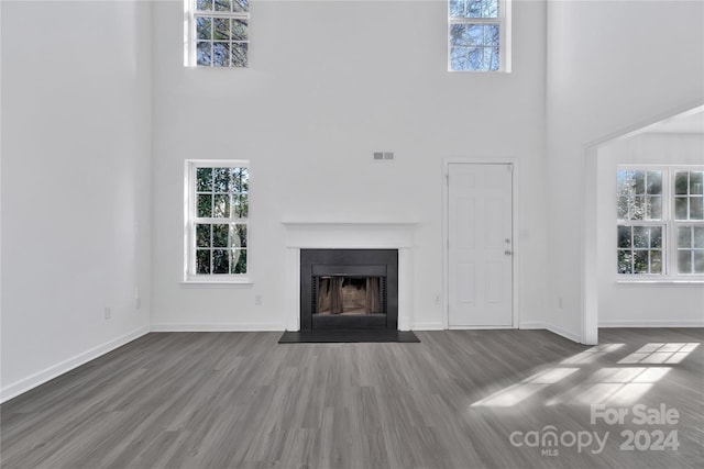 unfurnished living room featuring a towering ceiling and hardwood / wood-style flooring