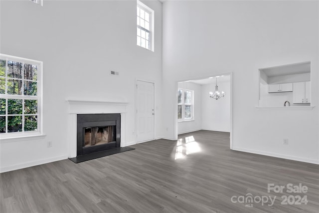 unfurnished living room with hardwood / wood-style flooring, plenty of natural light, and a high ceiling