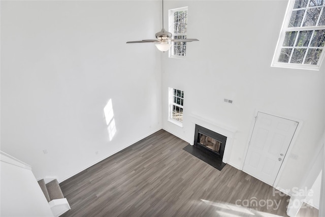 unfurnished living room featuring ceiling fan and dark wood-type flooring