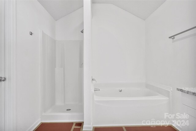 bathroom featuring vanity, vaulted ceiling, and shower with separate bathtub