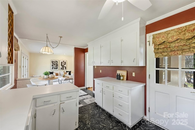 kitchen featuring decorative light fixtures, ceiling fan, white cabinetry, and ornamental molding