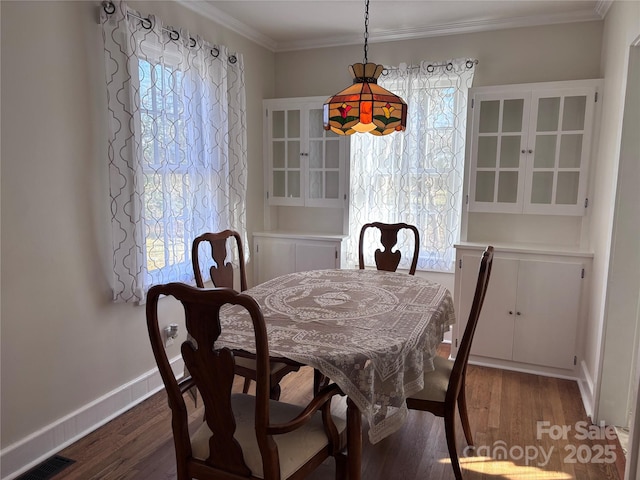 dining area featuring dark wood-type flooring, ornamental molding, and plenty of natural light