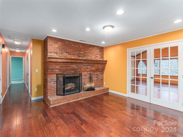 unfurnished living room featuring dark wood-type flooring, french doors, crown molding, a brick fireplace, and a textured ceiling