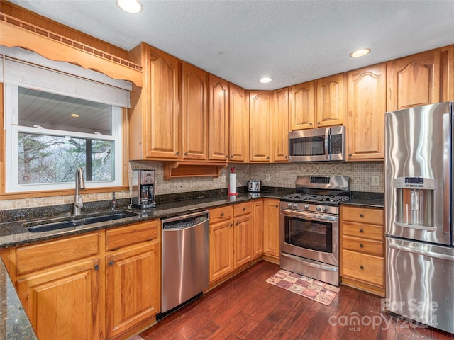 kitchen featuring dark stone counters, sink, stainless steel appliances, and dark hardwood / wood-style floors