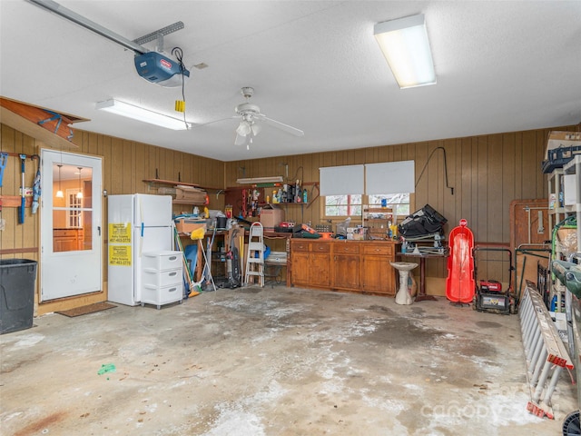 garage with a workshop area, wood walls, a garage door opener, and white refrigerator