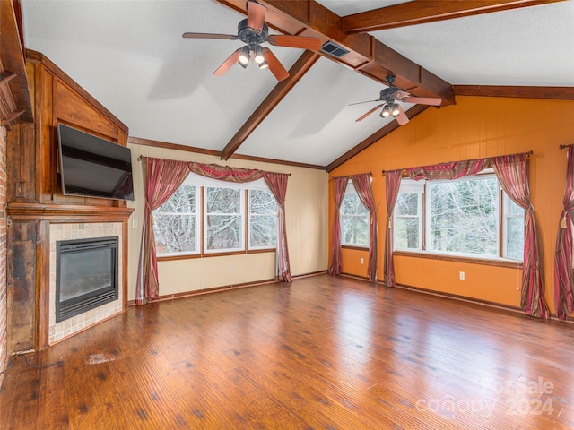 unfurnished living room featuring hardwood / wood-style floors, lofted ceiling with beams, a wealth of natural light, and a tiled fireplace