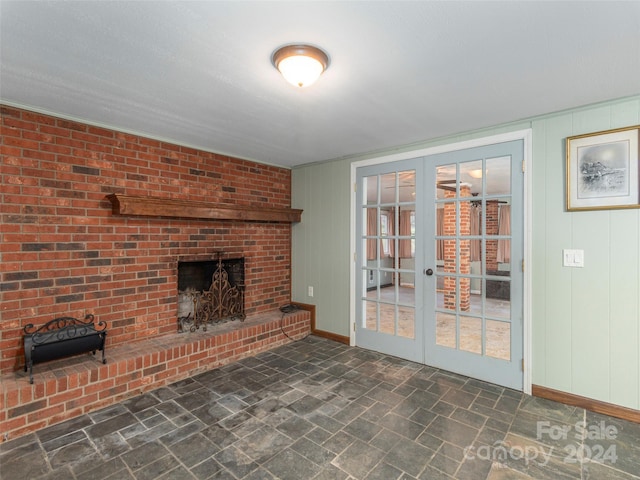 unfurnished living room with a brick fireplace and french doors