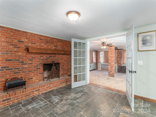 unfurnished living room with a fireplace, french doors, and ceiling fan