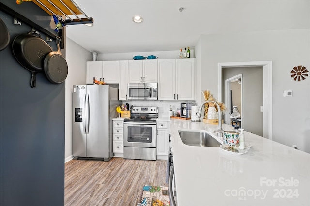 kitchen with sink, white cabinets, stainless steel appliances, and light hardwood / wood-style floors