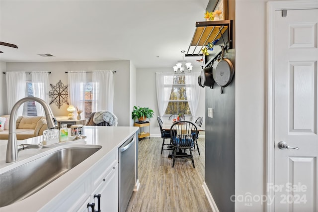 kitchen with white cabinetry, sink, stainless steel dishwasher, a chandelier, and light hardwood / wood-style floors