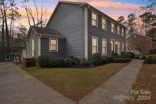 property exterior at dusk featuring a lawn