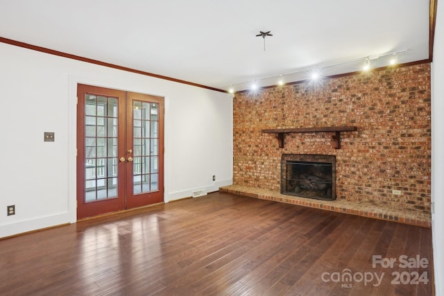 unfurnished living room featuring french doors, rail lighting, hardwood / wood-style flooring, and a brick fireplace