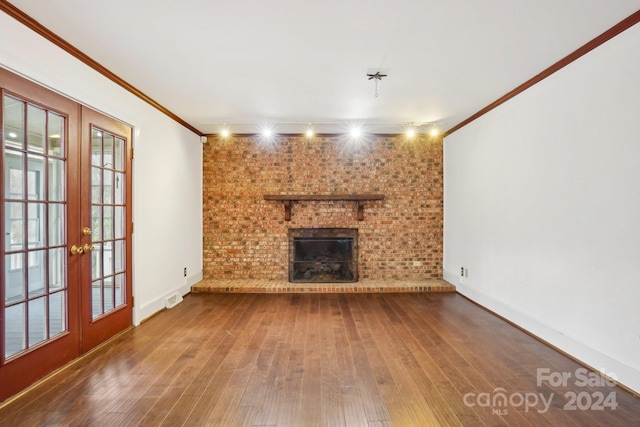 unfurnished living room featuring wood-type flooring, a brick fireplace, and brick wall