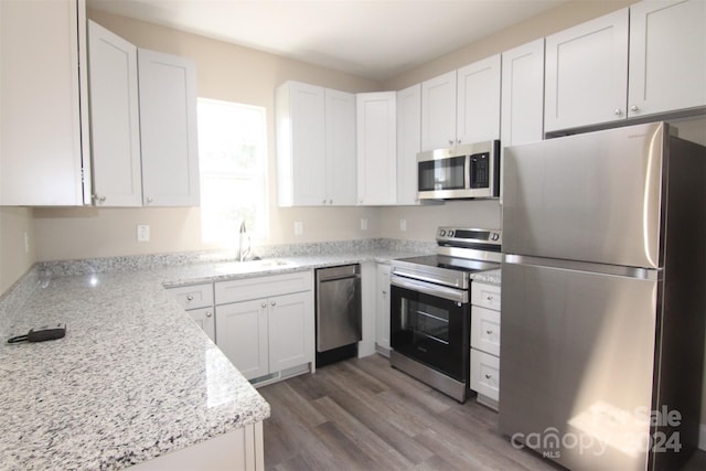 kitchen with light stone countertops, dark hardwood / wood-style flooring, stainless steel appliances, sink, and white cabinetry