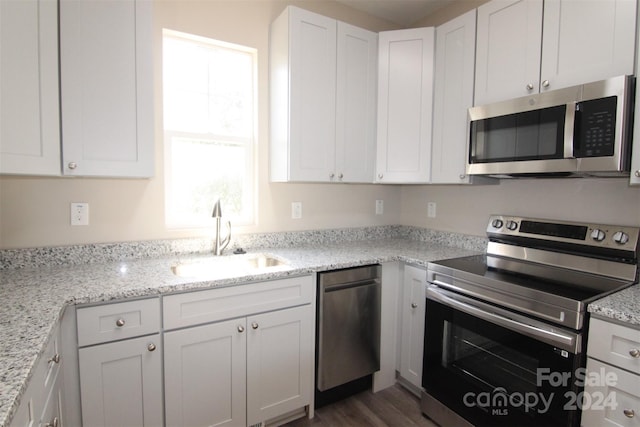 kitchen featuring white cabinets, sink, dark hardwood / wood-style flooring, light stone counters, and stainless steel appliances