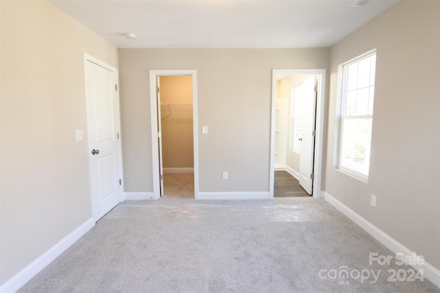 unfurnished bedroom with carpet, a walk in closet, and a closet