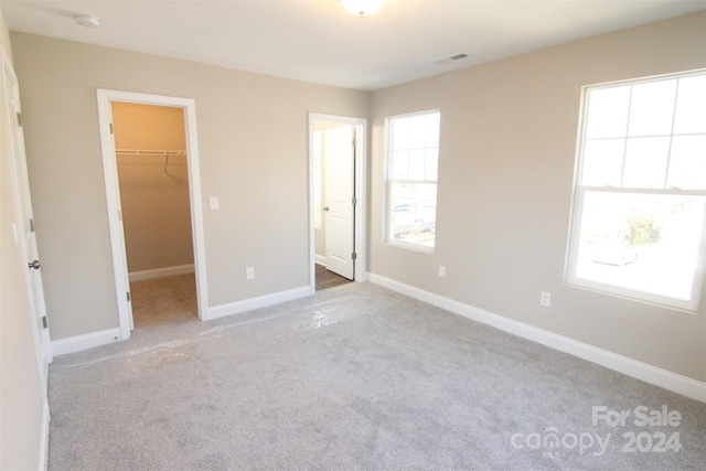 unfurnished bedroom featuring light carpet, a spacious closet, and a closet