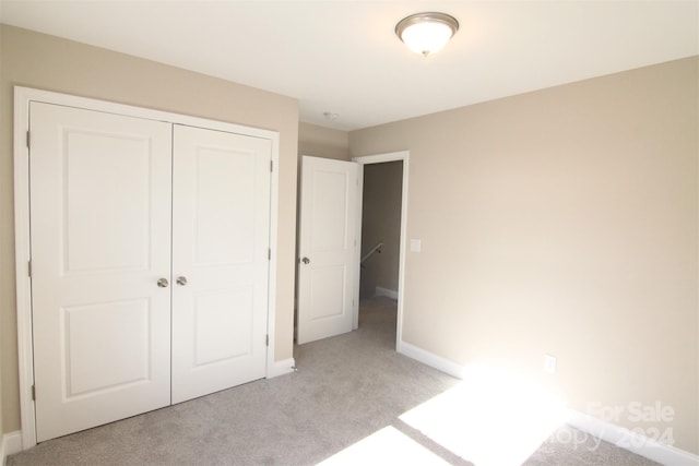 unfurnished bedroom featuring light carpet and a closet