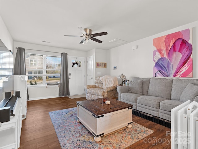 living room with dark hardwood / wood-style flooring, ceiling fan, and a healthy amount of sunlight