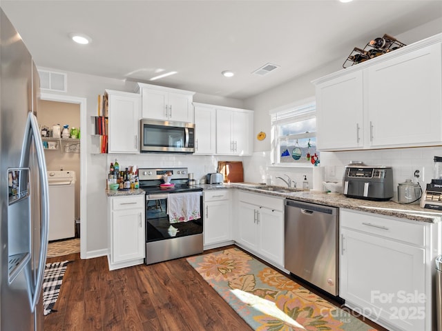 kitchen with washer / dryer, white cabinets, and appliances with stainless steel finishes